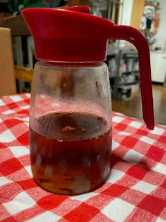 Red plastic container with a handle on a checkered tablecloth