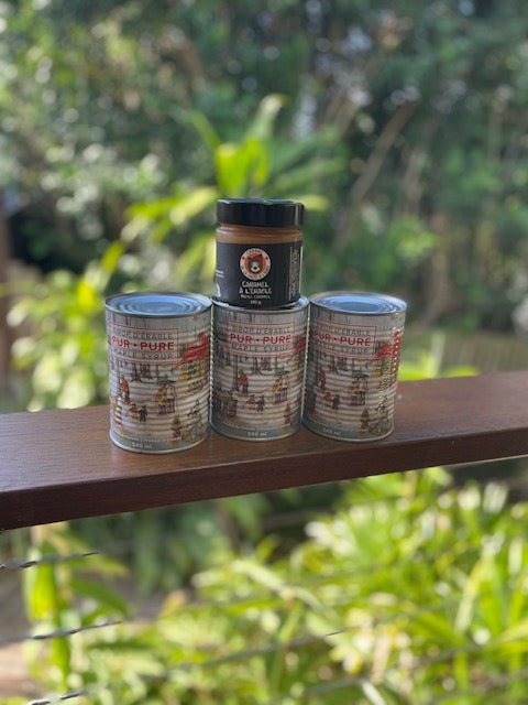 Three cans of 'Sur-Pure' pet food on a wooden surface with a natural background